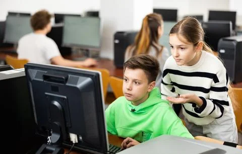 Schoolboy helping classmate to solve computer trouble in classroom Stockfoto's