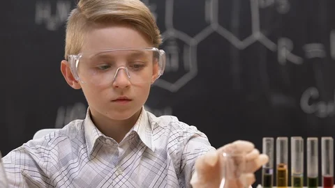 Schoolboy holding flask with red liquid and scratching head, wrong reaction Video stock 110628979