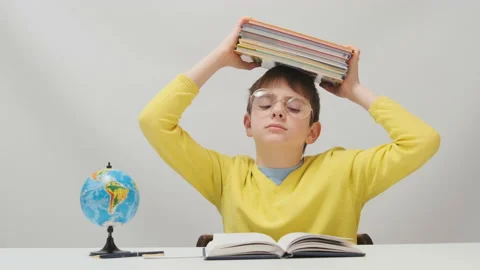 Schoolboy in large glasses holds stack of notebooks above head. Stock Footage 172490590