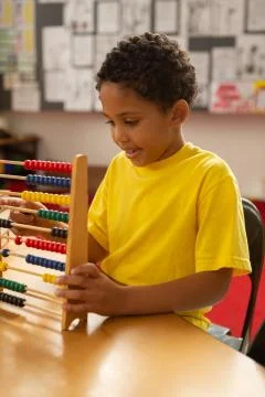 Schoolboy learning mathematics with abacus in a classroom 스톡 사진