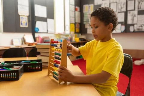 Schoolboy learning mathematics with abacus in a classroom Stock Photos