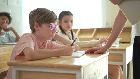 Schoolboy looking bored and distracted in classroom while classmates study Stock Footage 339328055