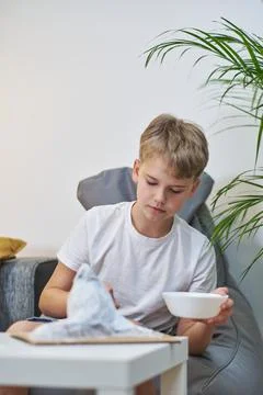 Schoolboy makes creative project in form of papier mache mountain. Stock Photos