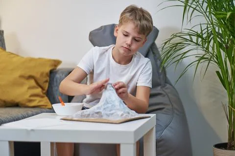 Schoolboy makes creative project in form of papier mache mountain. Stock Photos