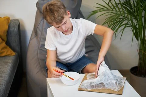 Schoolboy makes creative project in form of papier mache mountain. 스톡 사진