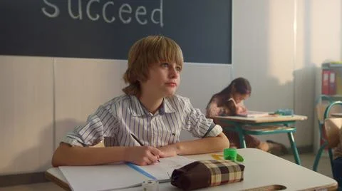 Schoolboy making notes in notebook. Smart boy writing in exercise book at lesson Stock Photos