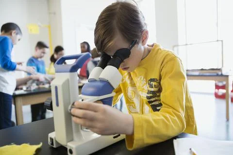 Schoolboy at microscope in science laboratory classroom Stock Photos