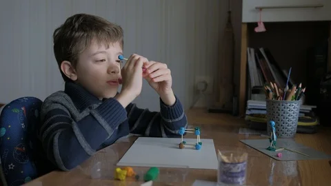 Schoolboy models the geometric shapes from plasticine and matches. Stock Footage 128988948