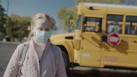 A schoolboy in a protective mask stands in front of a school bus. A Stop sign is Stock Footage 246758330