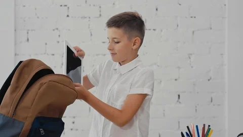Schoolboy puts a tablet computer in a backpack. Back to School. Stock Footage 92734257
