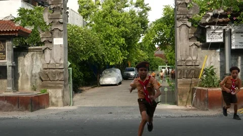 Schoolboy run from school gate towards camera, crossing the road 動画素材 52692586