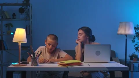 A schoolboy sits at a table in a room doing homework. Stock Footage 301913329