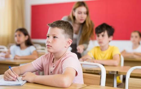 Schoolboy sitting in classroom during lesson in elementary school Stock Photos