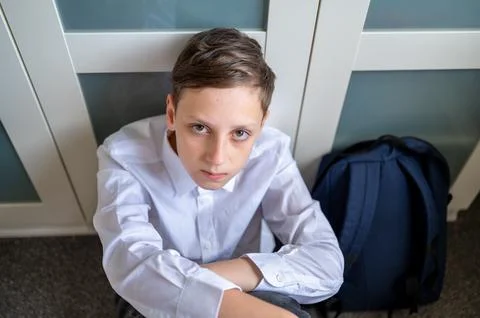 A schoolboy sitting on floor with backpack. Stock Photos