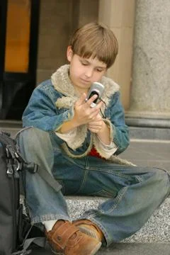 Schoolboy sitting on steps using phone Foto stock
