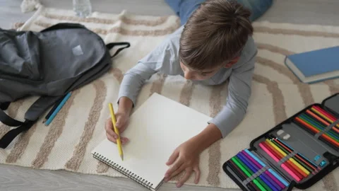 A schoolboy Small caucasian boy play at home draw on the floor Stock Footage 249813149