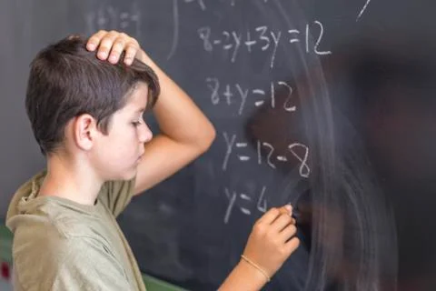 Schoolboy solving a problem on a blackboard. Stock Photos