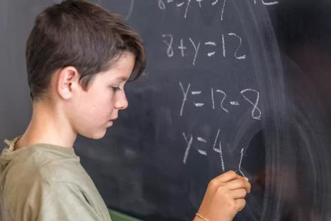 Schoolboy solving a problem on a blackboard. Stock Photos