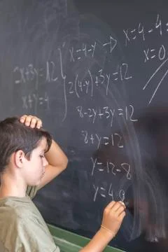 Schoolboy solving a problem on a blackboard. Stock Photos