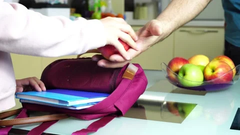 A schoolboy stacks a red apple in a school bag. Stock Footage