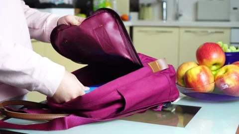 A schoolboy stacks a red apple in a school bag Stock Footage 135457343