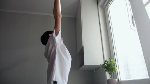 Schoolboy stretches body as looking through window in room Stock Footage 308434892