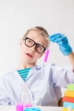 A schoolboy studies multi-colored substances in test tubes, conducts experime Stock Photos