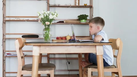 The schoolboy is studying on a laptop in a spacious, bright living room. Stock Footage 310941822