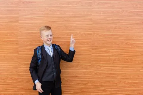 Schoolboy in suit points to the side with his hand Stock Photos