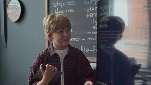 Schoolboy with Tablet Explaining Robotics Code on Screen in Classroom Stock Footage 339196822