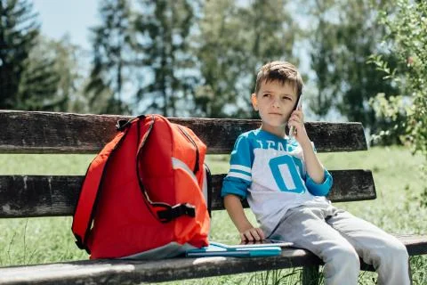 Schoolboy taking a break on a bench and making a phone call Stock Photos