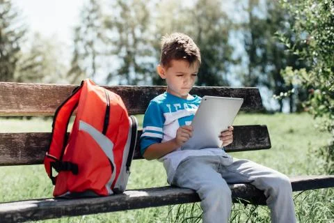 Schoolboy taking a break playing with a tablet on a bench Stock Photos