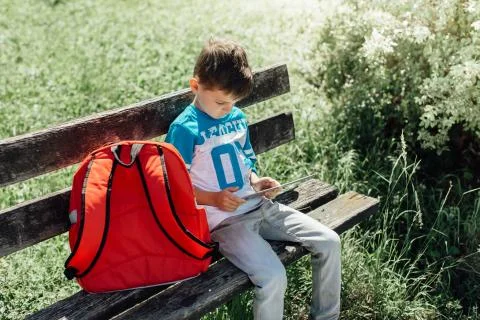 Schoolboy taking a break playing with a tablet on a bench Stock Photos