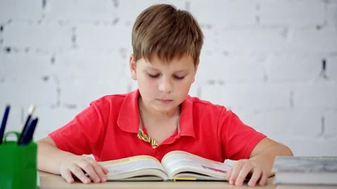 Schoolboy tired of reading the textbook Stock Footage 92038337
