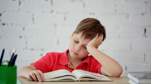 Schoolboy tired of reading the textbook Stock Footage 92038778
