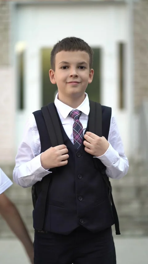 Schoolboy in uniform with backpack descends school stairs, stops  Stock Footage 344312782