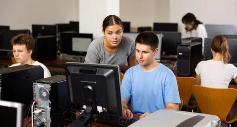 Schoolboy using computer and teacher helping to him in class room Stock Photos