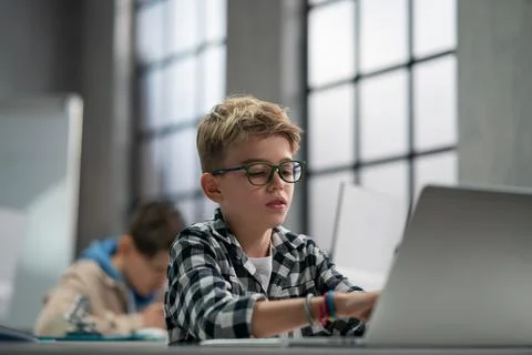 Schoolboy using computer in classroom at school 库存照片
