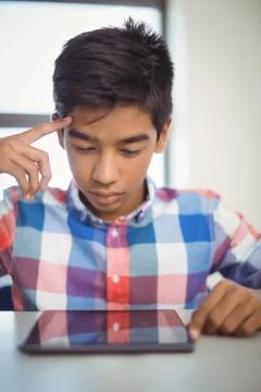 Schoolboy using digital tablet at desk 스톡 사진
