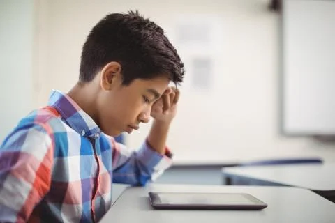 Schoolboy using digital tablet at desk Foto stock