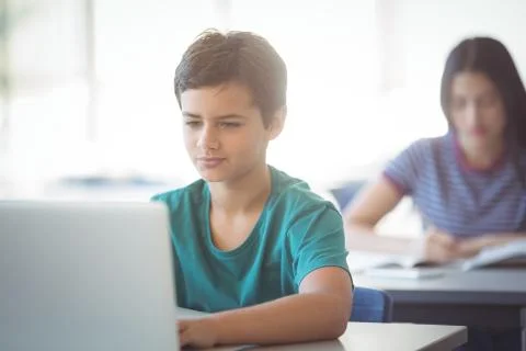 Schoolboy using laptop in classroom 写真素材