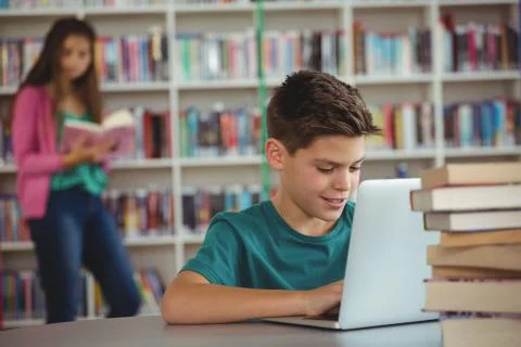 Schoolboy using laptop in library 스톡 사진