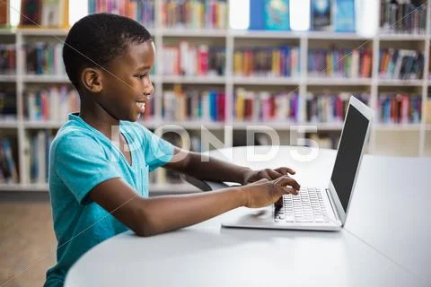 Schoolboy Using Laptop In Library At School