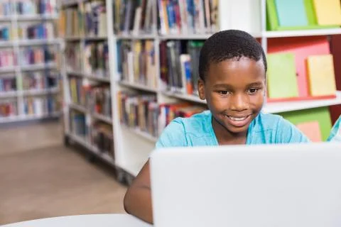 Schoolboy using laptop in library at school 스톡 사진