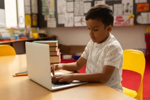 Schoolboy using laptop at table in a classroom 스톡 사진