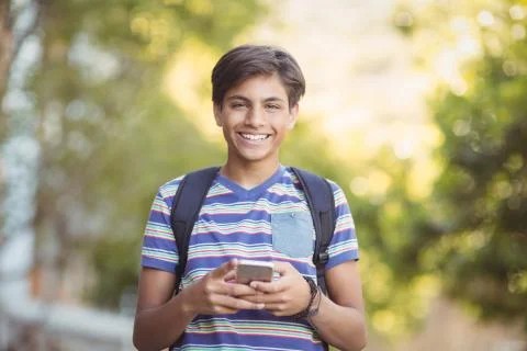 Schoolboy using mobile phone in campus at school Foto stock
