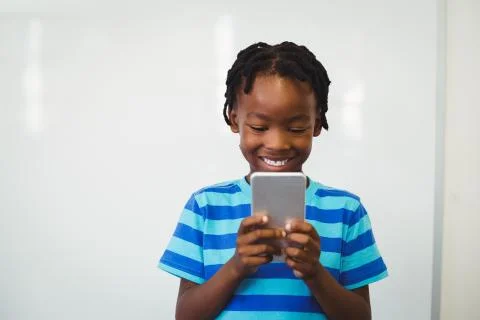 Schoolboy using mobile phone in classroom Foto stock