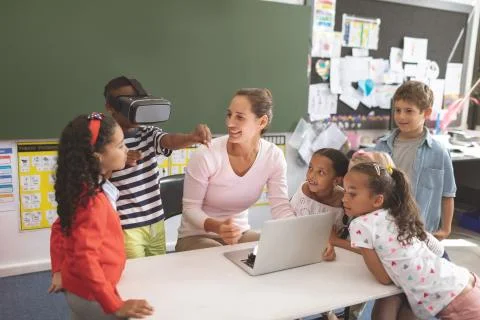 Schoolboy using virtual reality headset at school in classroom with his 스톡 사진