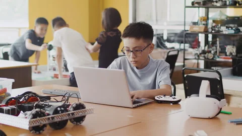 Schoolboy working on a laptop in a class at a robotics lesson and thinking about Stock Footage 244406848