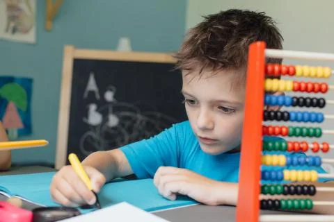 Schoolboy working on math homework with an abacus Stock Photos